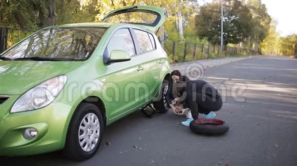 两个女人用千斤顶把车抬起来换一个被刺破的轮胎视频的预览图