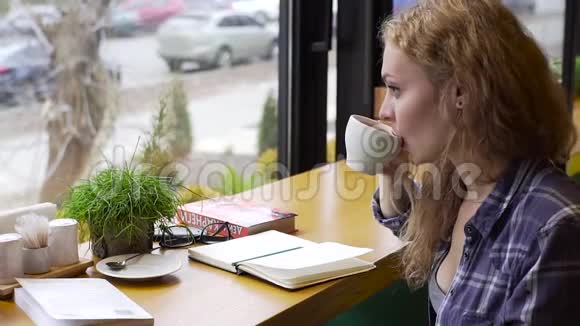 年轻女子在自助餐厅学习时喝咖啡并做笔记动作缓慢视频的预览图