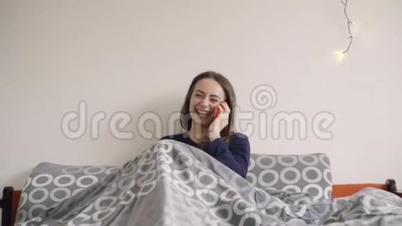 快乐的年轻女子在家卧室打电话给智能手机视频的预览图