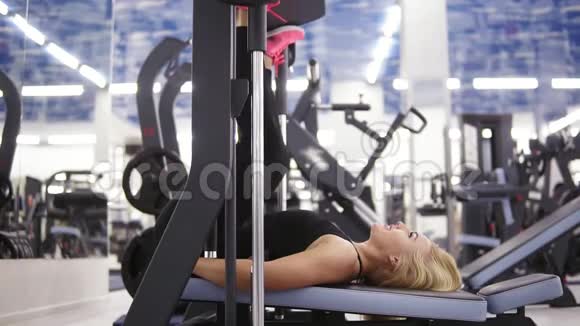 漂亮的白种人年轻的金发美女在健身房锻炼时身体健康面带微笑用马什丁压腿视频的预览图
