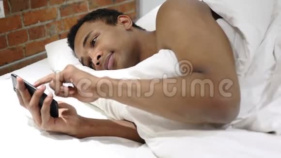 夜间在智能手机上躺在床上打字的非洲人视频的预览图