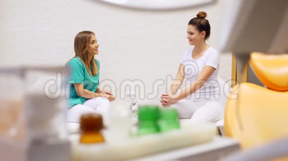 一位牙医和她的助手坐着等病人的录像视频的预览图