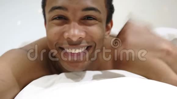 快乐的非洲男人躺在胃床上竖起大拇指视频的预览图