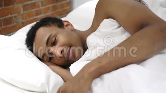 躺在床上的非洲人用手机聊天谈判视频的预览图