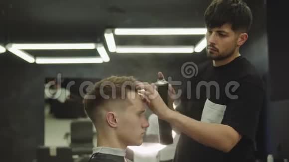 理发师在理发店理发后用喷发剂做发型年轻英俊的高加索男人视频的预览图