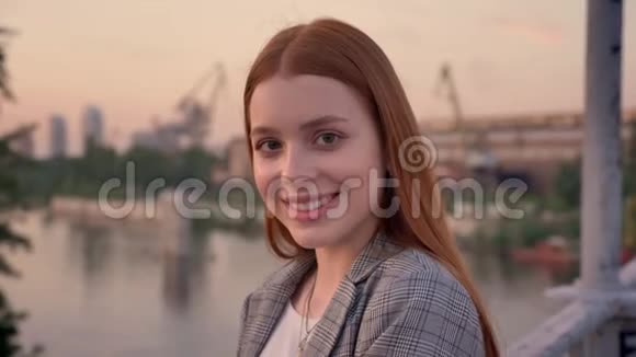 年轻漂亮女人的肖像姜发站在桥上望着镜头微笑着日落视频的预览图
