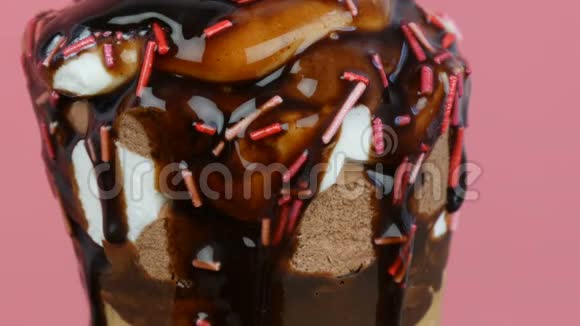 巧克力酱糖霜在粉红色背景的华夫饼杯中流过冰淇淋视频的预览图