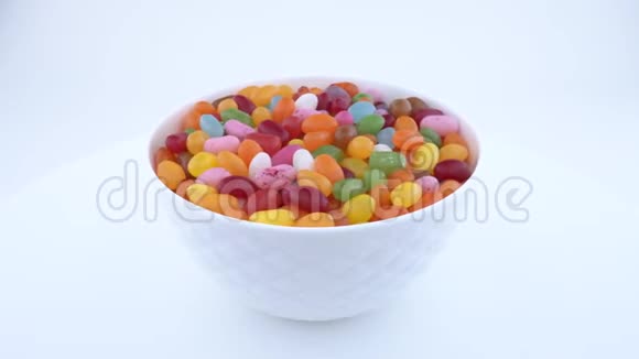 一堆小豆形糖冻糖果在转盘上的白色碗中旋转孤立无援视频的预览图