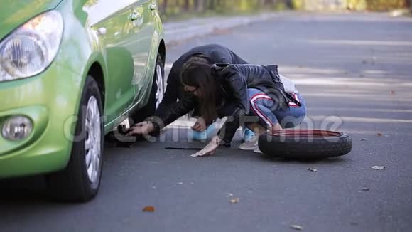 两个女人用千斤顶把车抬起来换一个被刺破的轮胎视频的预览图