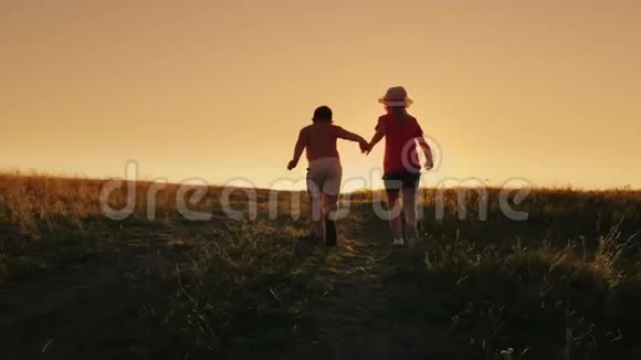 两个无忧无虑的孩子一个女孩和一个六岁的男孩一起上山牵着手概念快乐视频的预览图