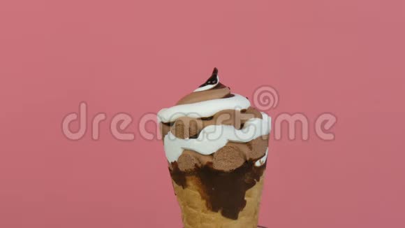 巧克力酱糖霜在粉红色背景的华夫饼杯中流过冰淇淋视频的预览图