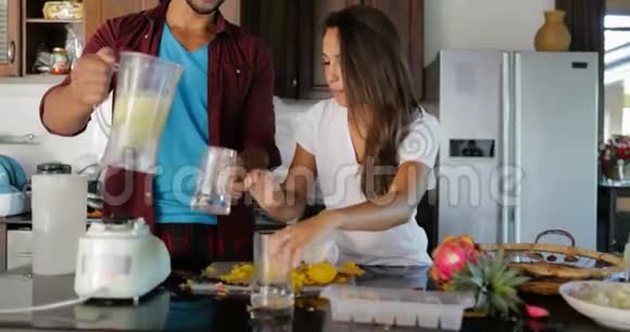 一对夫妇在酒杯里倒入鲜榨果汁男人和女人在厨房里一起谈幸福的微笑视频的预览图
