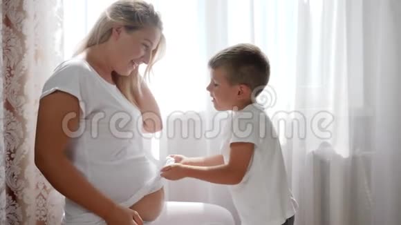 小孩头枕在光房里怀孩子的大肚子上视频的预览图