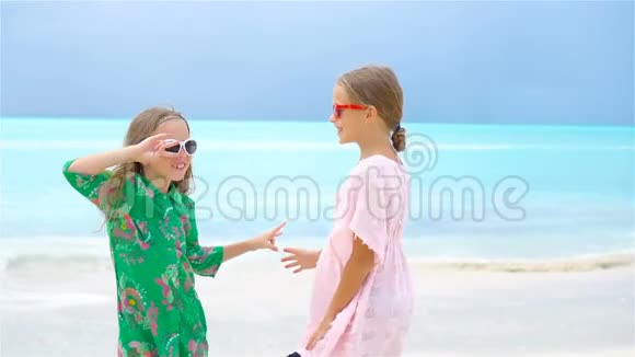 可爱的小女孩在热带海滩上玩得很开心一起玩背景蓝色的水和天空视频的预览图