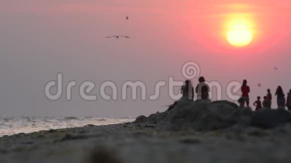 日落时沿着海洋行走的一群人视频的预览图
