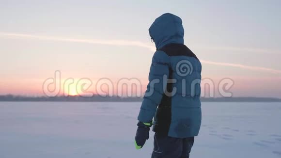 日落时一个孩子在雪地里翻筋斗新鲜空气中的乐趣和游戏视频的预览图