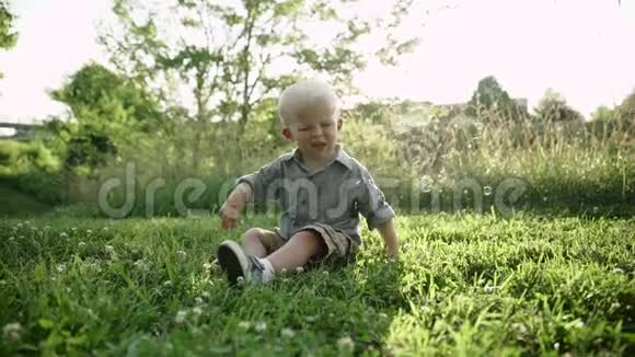 小男孩坐在草地上户外玩肥皂泡慢动作全高清视频的预览图