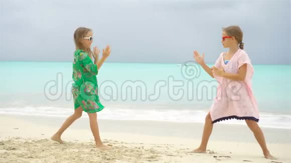 可爱的小女孩在热带海滩上玩得很开心一起玩背景清澈的水和蓝天视频的预览图