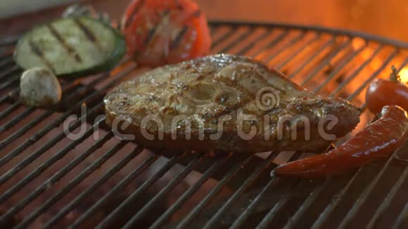 白鱼牛排配上蔬菜辣椒西葫芦和西红柿背景火视频的预览图
