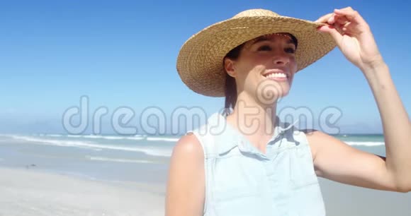在海滩散步时戴着帽子的美女视频的预览图