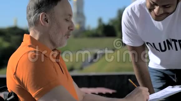 微笑的志愿者帮助一个轮椅司机填写信息视频的预览图