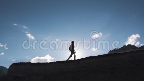一个旅行者在山峦和天空背景下的剪影那个旅游女孩正沿着山顶走视频的预览图