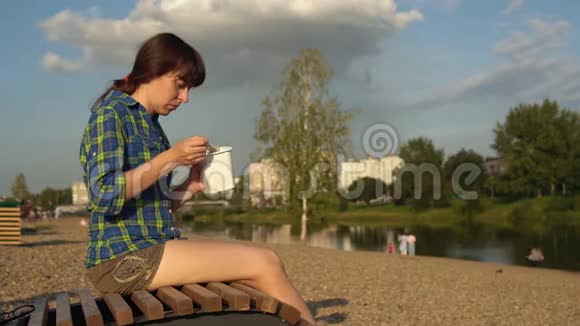 年轻女子从甲板椅上的盒子里吃方便面视频的预览图