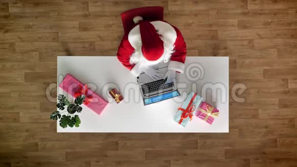 圣诞老人在办公室工作手提电脑打字鸟瞰自上而下拍摄视频的预览图