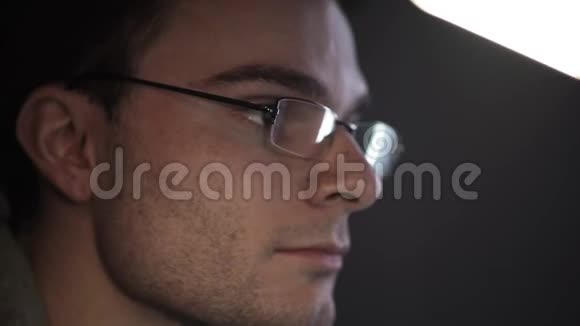 戴眼镜的年轻兴奋男子夜间在电脑上工作的肖像视频的预览图