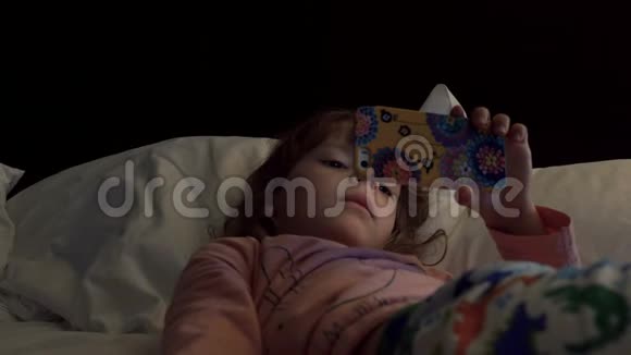 儿童躺在床上使用智能手机2视频的预览图