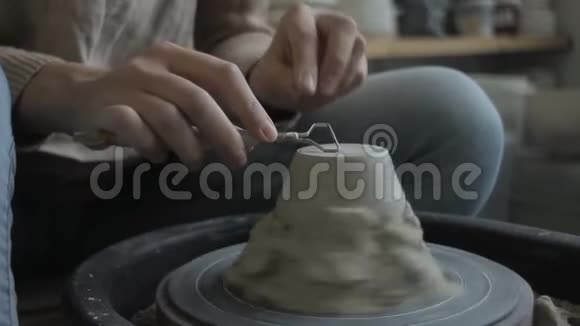年轻的陶匠正坐在现代车间里抛光粘土花瓶视频的预览图