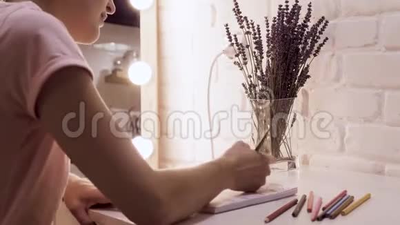 女孩在笔记本上画画背景灯中化妆镜砖墙晚上好视频的预览图