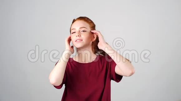 开朗的年轻红发女孩跳舞看着白色背景的相机慢动作视频的预览图