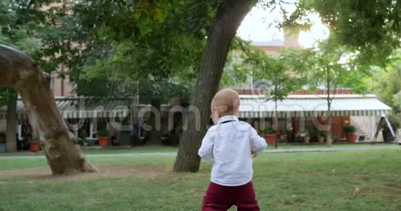 漂亮的小孩光着脚在公园的绿草上散步视频的预览图