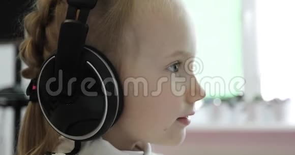 一个小女孩在耳机上听音乐视频的预览图