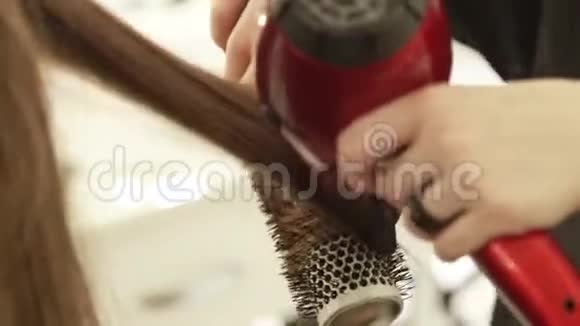 理发师使用烘干机烘干女性头发并在美容工作室美发后使用梳子进行造型关门视频的预览图