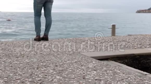 穿牛仔裤的腿和码头上的棕色皮靴视频的预览图