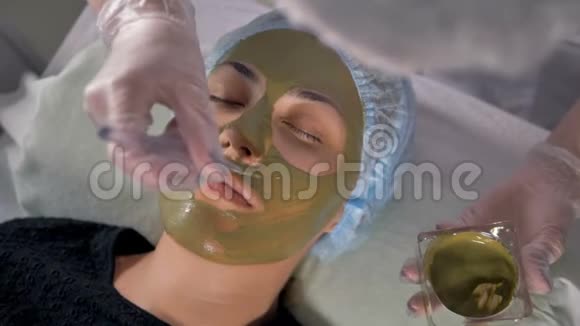 顶部的女性脸上覆盖着绿色的泥面膜视频的预览图