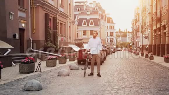 日落时分时尚留胡子的男子骑着自行车在街上行走的慢动作视频视频的预览图