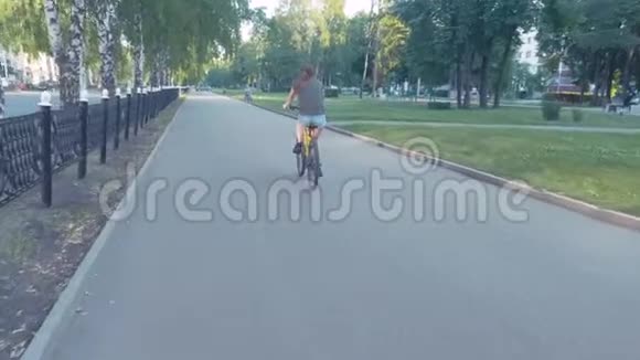 一个女孩骑着花篮在马路上骑着自行车在城市里探险慢的稳定的镜头视频的预览图