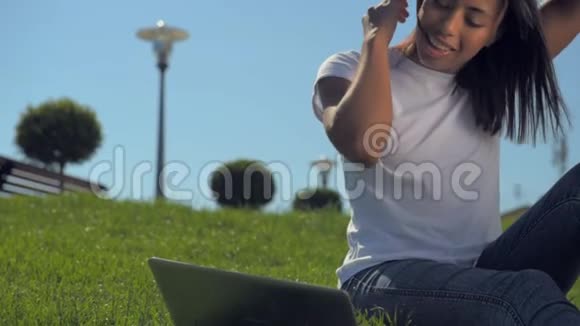 殴打坐在草地上拿笔记本电脑的女孩视频的预览图