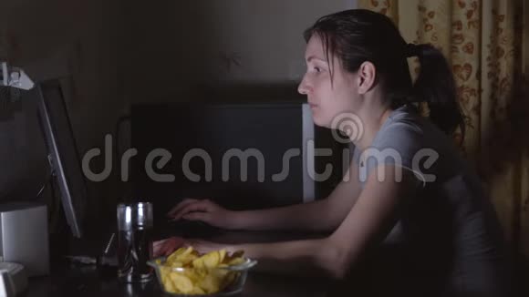 年轻女子坐在电脑前吃薯片视频的预览图