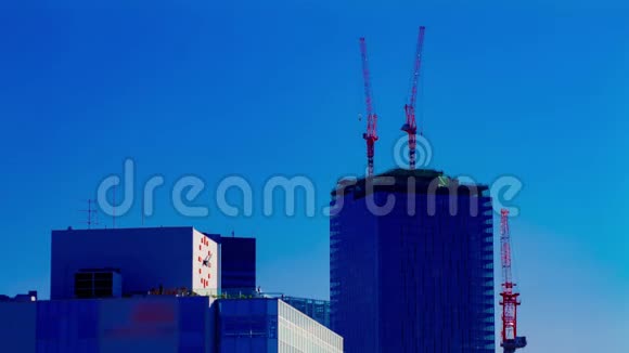 东京蓝天后面建筑顶部的起重机移动的时间间隔视频的预览图
