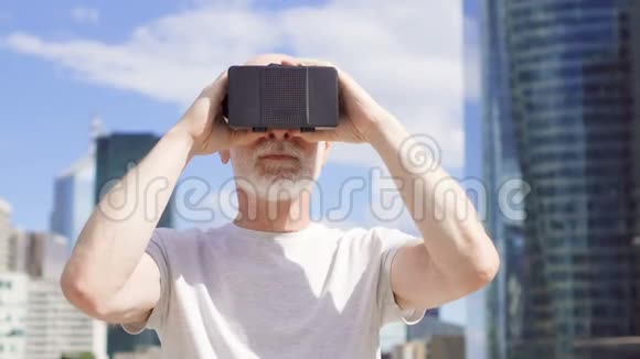使用虚拟现实眼镜站在商业区的老人背景摩天大楼视频的预览图