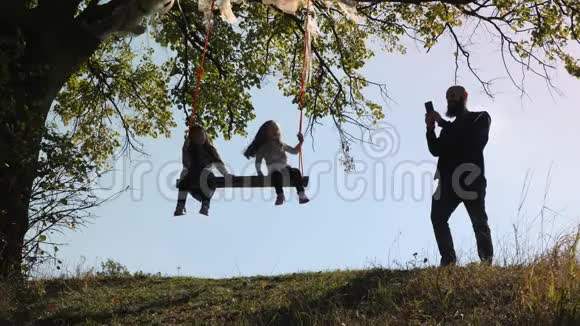 父亲拍了两个女儿在树下荡秋千的照片视频的预览图