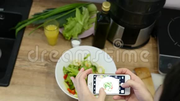 女人用智能手机拍照把绿色沙拉和黄瓜与红番茄放在框叶上视频的预览图