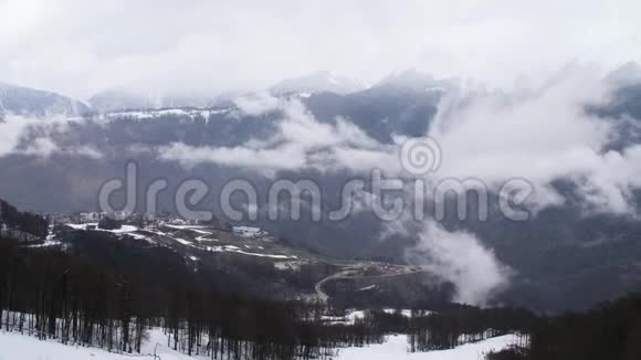 山顶景观和小型冬季度假胜地笼罩在山峰和山麓的乌云视频的预览图