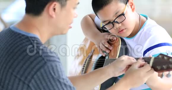 年轻的亚洲男孩由教练练习吉他视频的预览图