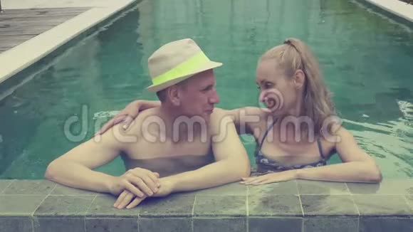 爱的一对夫妇男人和女人在热带度假胜地的游泳池里休息色调和复古效果视频的预览图