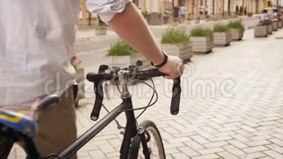欧洲小镇老街上一位年轻时尚男士骑着固定齿轮的运动自行车行走视频的预览图